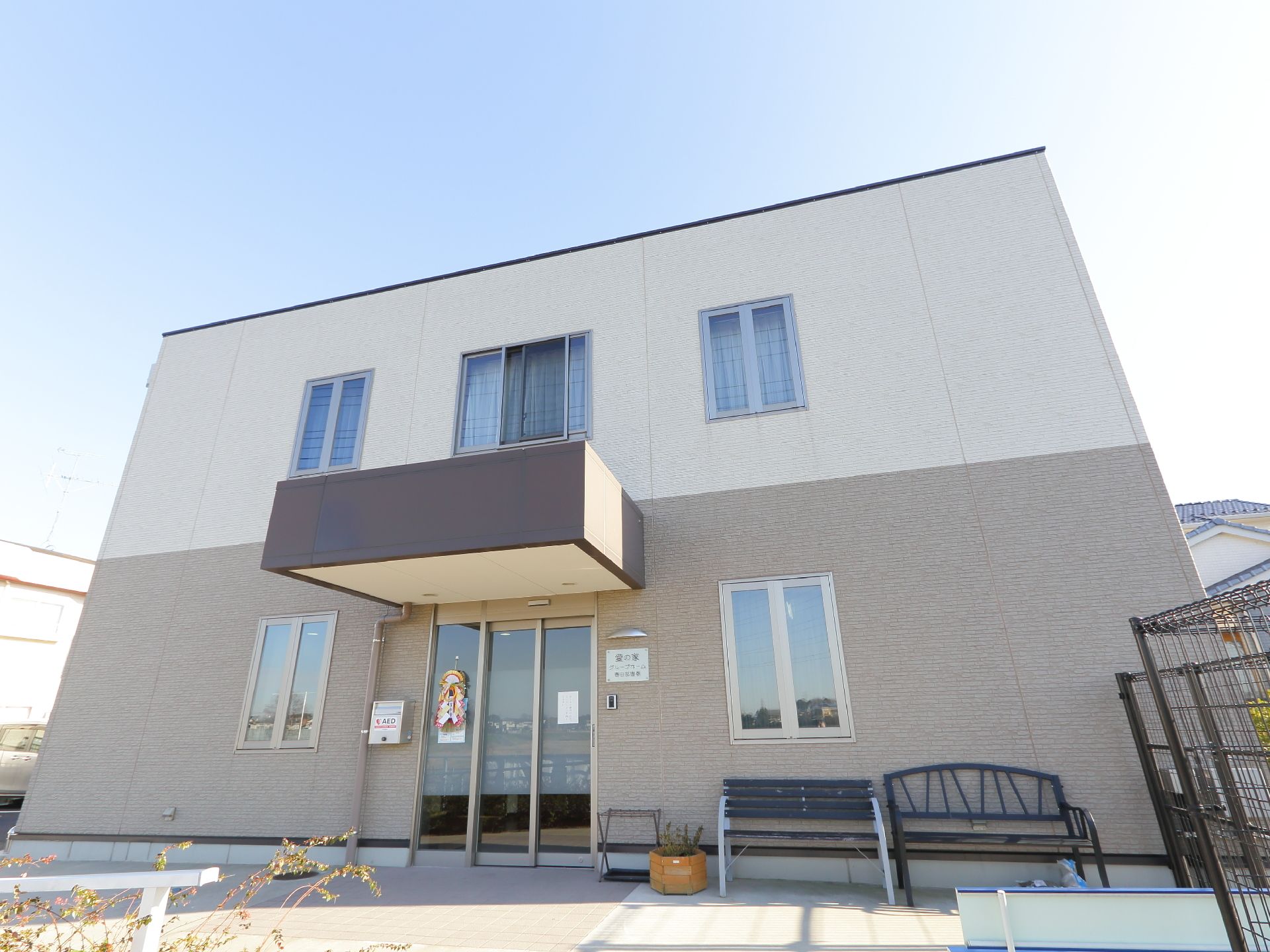 長方形の建物に、入り口前に設置された屋根が付き出したデザインだ。窓は中央寄りの場所にある。また外にベンチが置いてある。