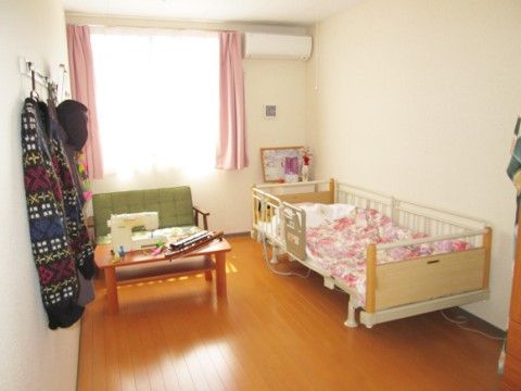 明るい色の寝具やお持ち込みのミシンが見える入居者様の居室