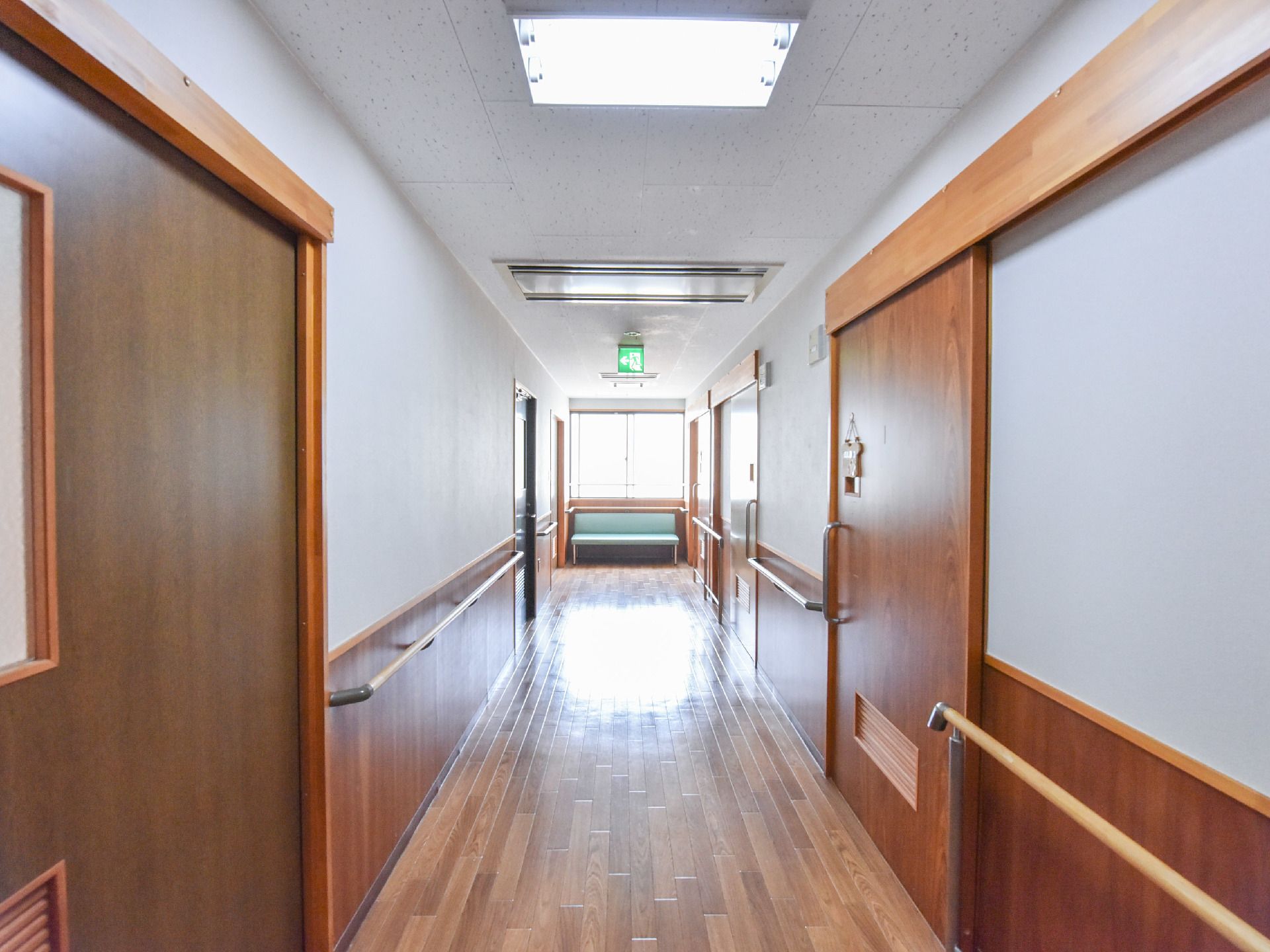 廊下には、木目が美しい材料が使われている。また廊下の手すり下にも木材を採用して、ドアとドアレールの枠にも木目が見える。