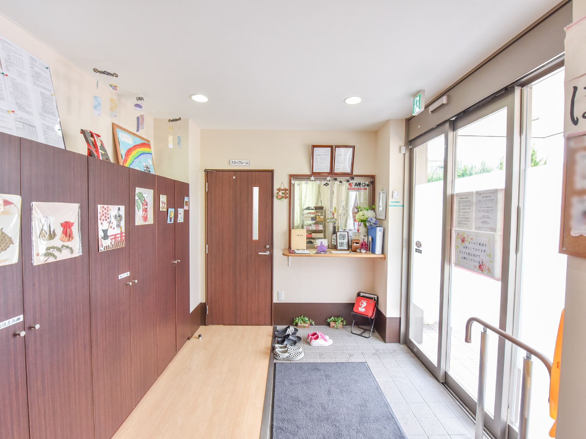 建物に入るとすぐ右に受付・スタッフルームがあり、正面は下駄箱が並んでいる。出入り口の前に手すりが付いている。