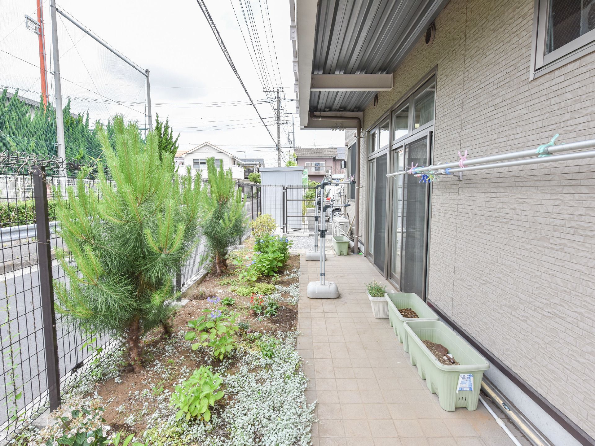 バルコニーは建物に沿って広く作られており、洗濯物を干す竿も多くある。木や花が植えられているほか、プランターも置かれている。