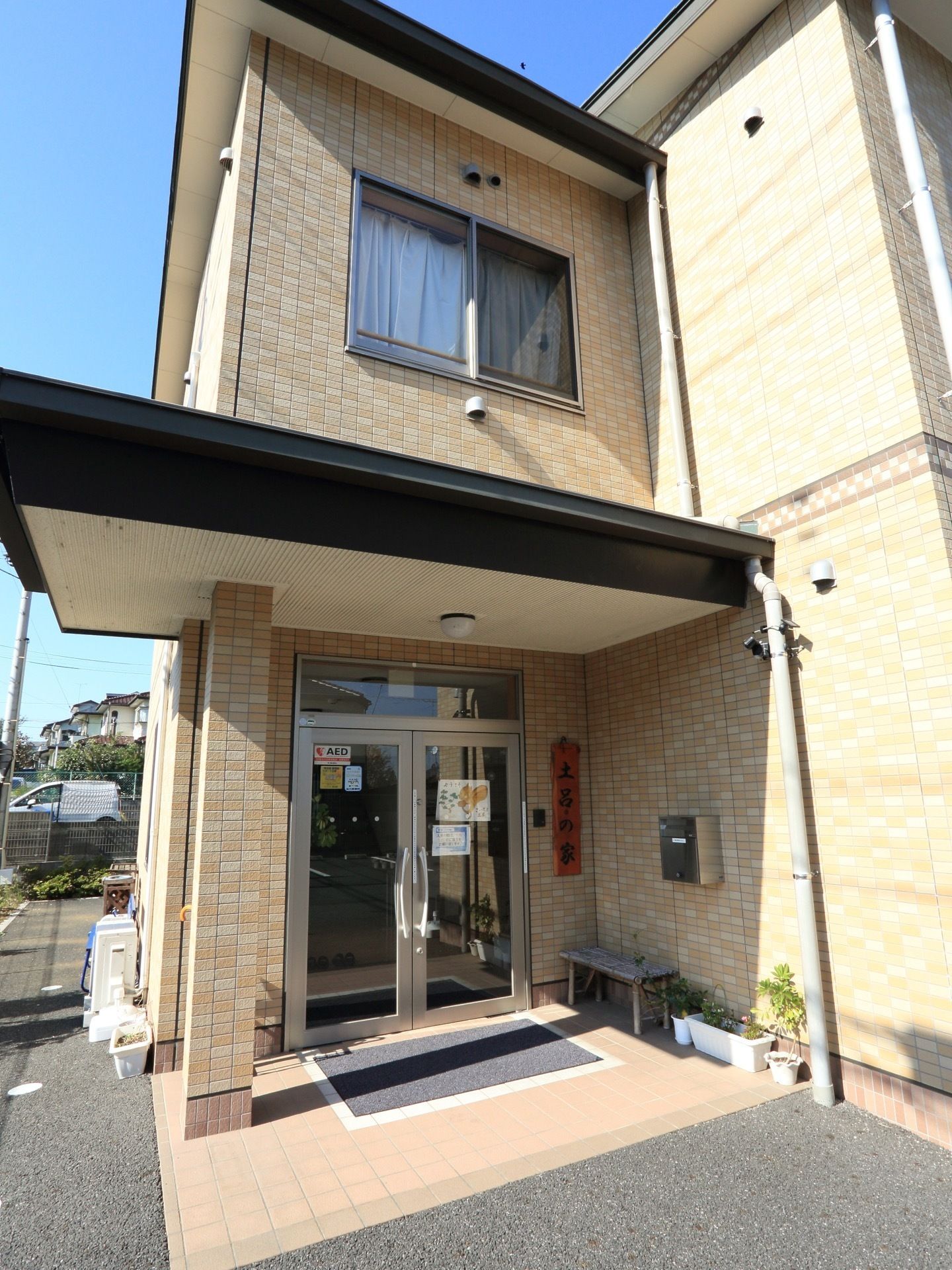 玄関ドアの脇に置いてある簡易ベンチは、居住者様がお散歩から戻った時などに腰を下ろし一休みする場所として重宝している。