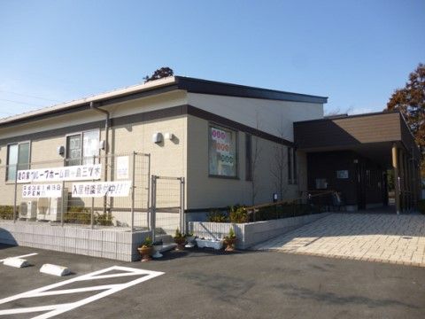 駐車場からエントランスへとスロープの伸びる白い平屋