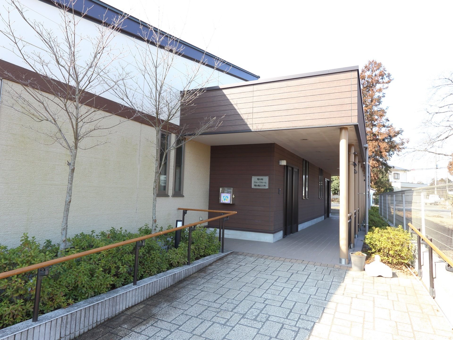 エントランスの壁には郵便受けがあり、看板を設置している。また入り口のスロープには、手すりが取り付けられている。