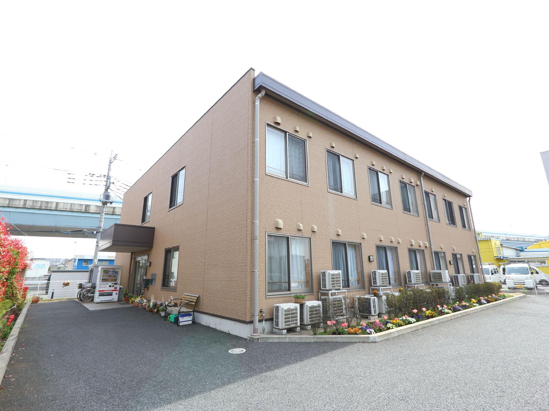 薄いブラウンの外壁の一面に14組の窓が並んだ２階建ての建物
