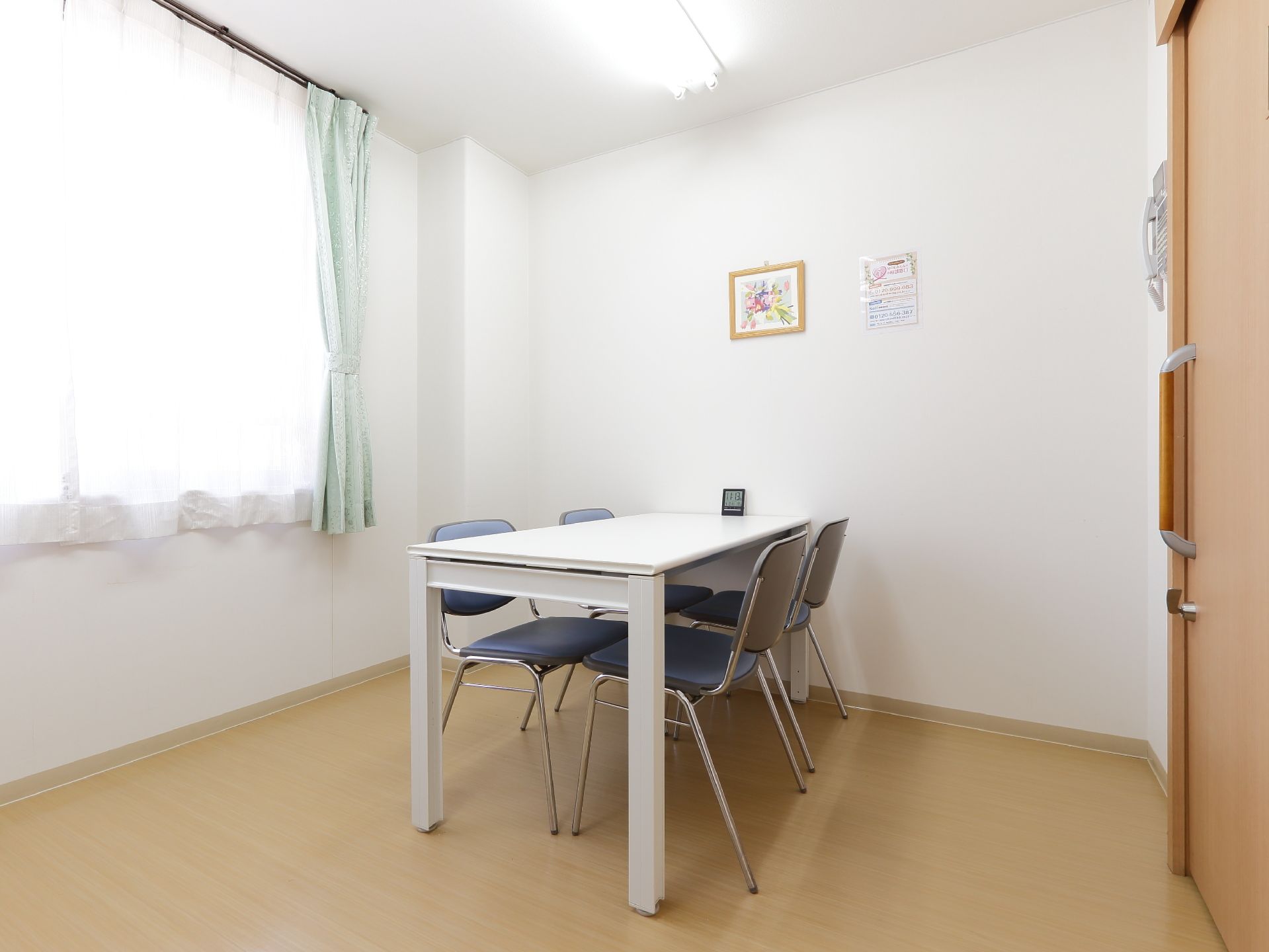 椅子４脚とテーブルが設けられている。窓が大きく日当たりが良い。壁には絵が飾られている。扉はスライド式となっている。