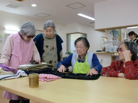 テーブルの上の衣類を囲んで確認する４人のシニア女性
