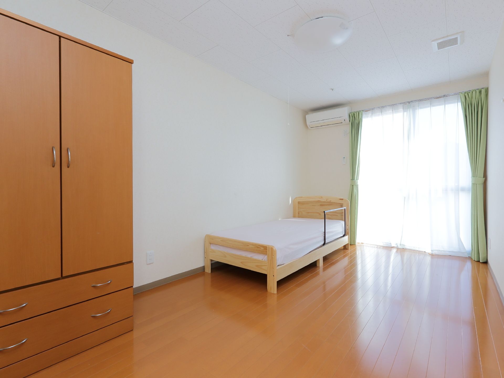 手すり付きの小さなベッドを設置したフローリングの部屋