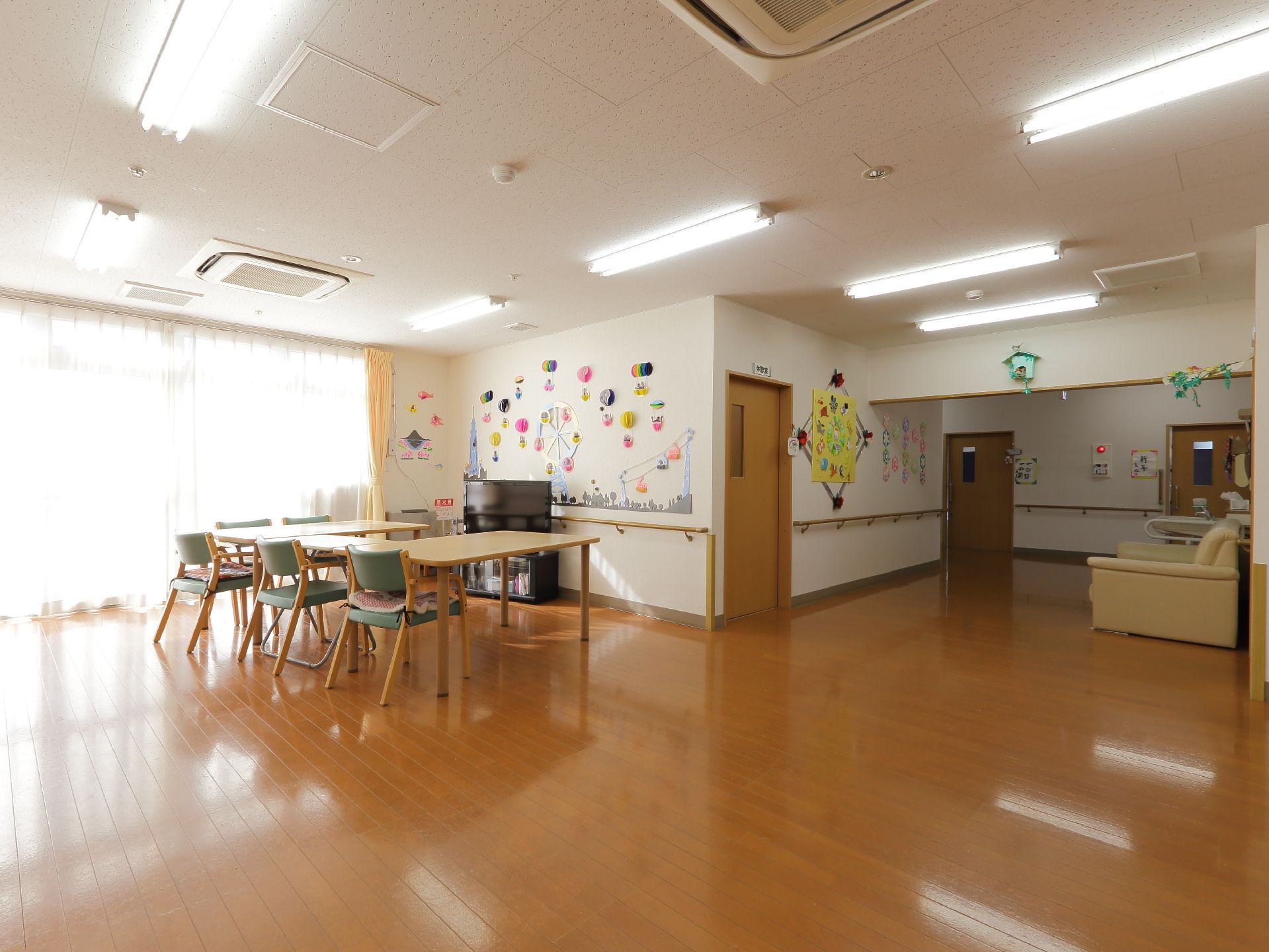 テーブルと椅子が設けられている空間である。壁には装飾がほどこされている。アイボリー色のソファが設けられている。