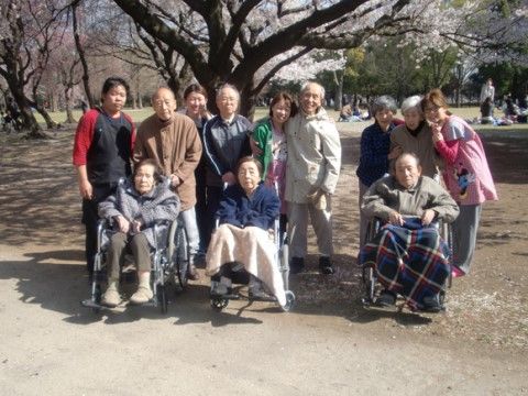 桜の木の下で肩を寄せ合って記念撮影をする12人の男女