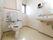 窓の付いたスペースの広い洋式トイレの様子。便座の両脇には手すりが付いており、背もたれパッドもある。洗面台が設けられているので便利である。