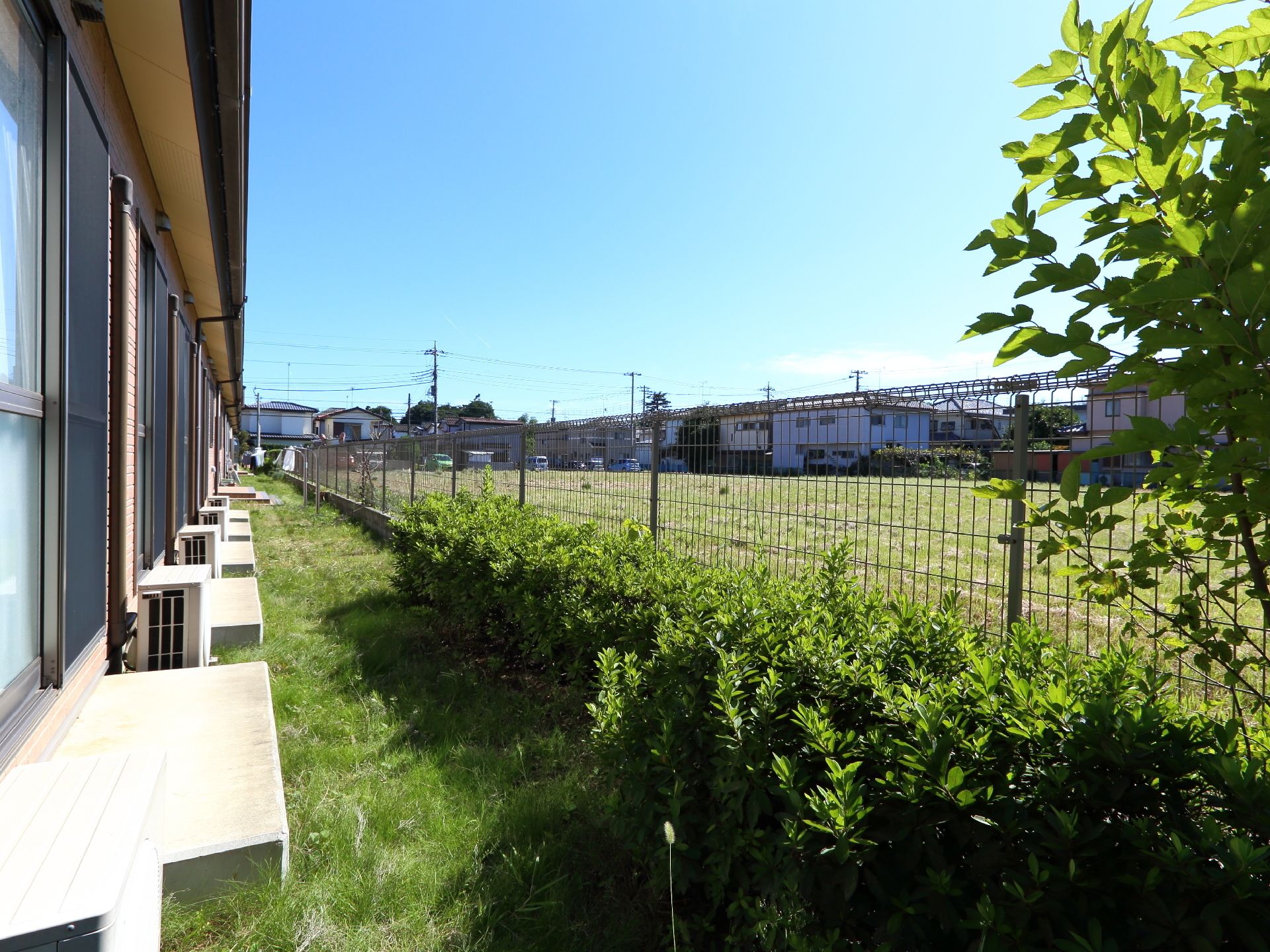 平屋の施設の各部屋からは外に出ることができるよう、コンクリートの台が設けられている。緑の草と木の植え込みが、夏場の熱気を奪ってくれる。