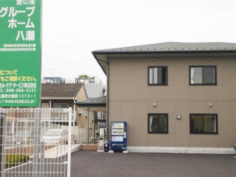 玄関脇に自動販売機の設置されたアッシュブラウンの建物