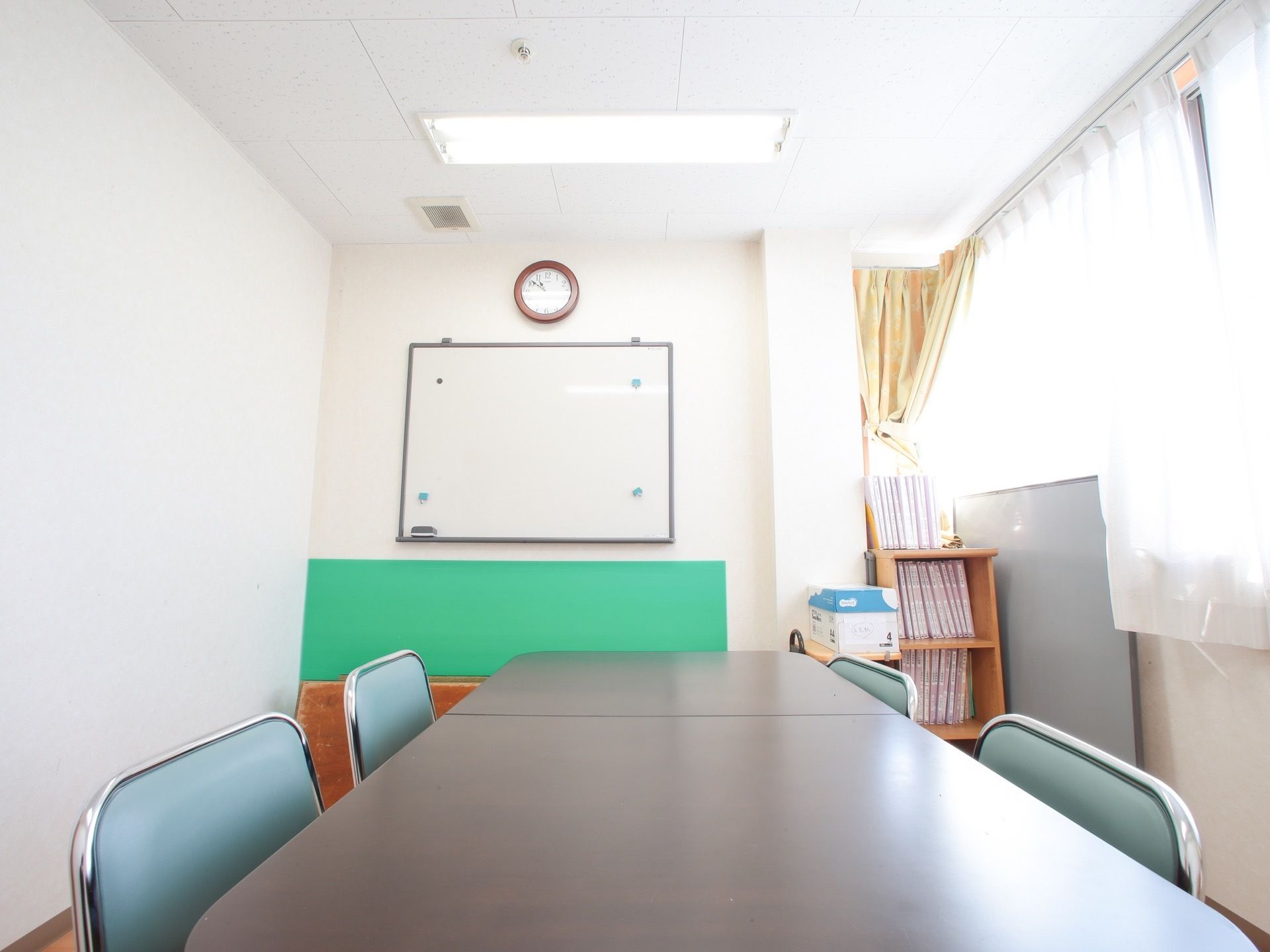 談話室の中央にはテーブルと椅子が4脚置かれている。コンパクトな部屋の壁にはホワイトボードが掛けられている。