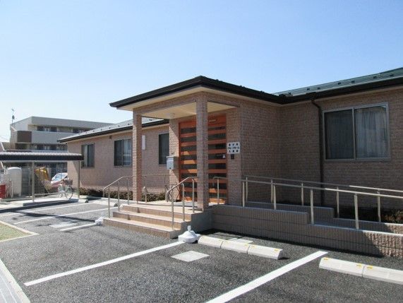 正面入口の前に４台分の駐車場を備えた茶色い外壁の平屋