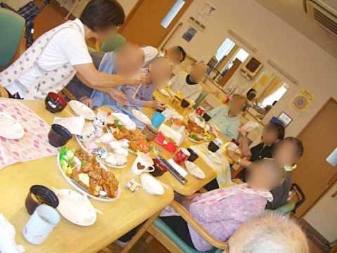 テーブル上に並ぶさまざまな料理を囲んで食事をとる９名