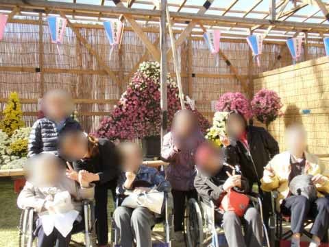 前後4人ずつ並び、が飾り付けられた花の前で撮影する記念写真