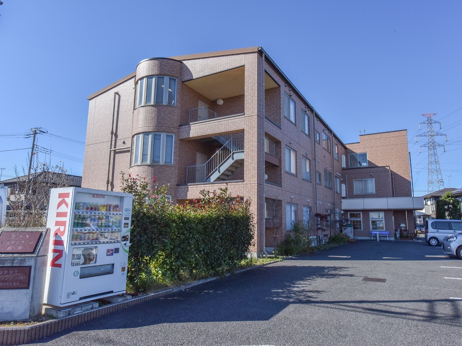茶系のタイル調の外観の３階建ての建物である。エル型構造で、横には、外階段があり、側面に半円型のフロア部分が飛び出た設計になっている。