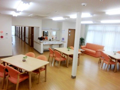 大きな窓があるダイニングには４人掛けテーブルがあり、オレンジの椅子やソファーがアクセントになっている。入口付近には手洗いコーナーもある。