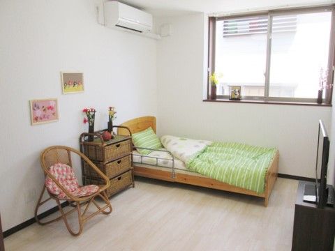 白に統一された内装にこぢんまりとした家具を備えたワンルーム