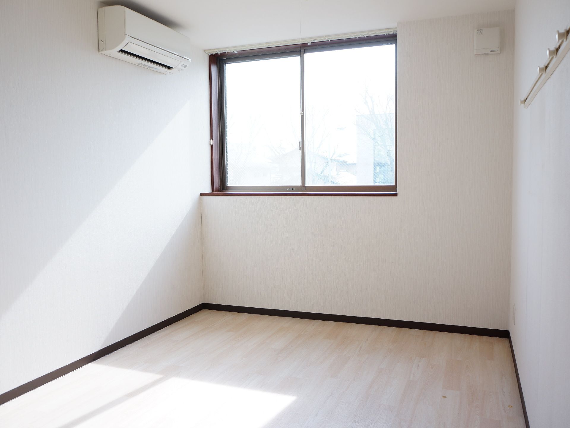 出窓からはたくさんの光が入ってくる。空調がついている。ハンガーが掛けられる場所もあり、便利である。壁全体が白で部屋が広く見える。