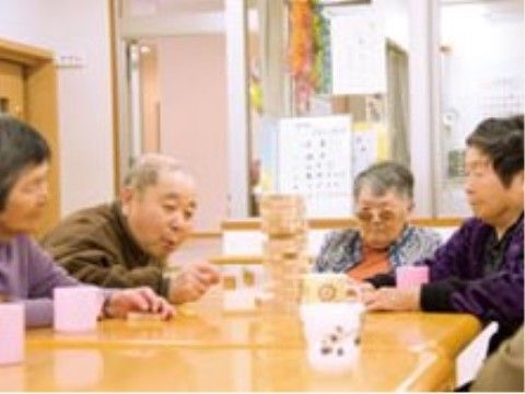 テーブルの上に置いた木製のパズルを楽しむ４人のシニア