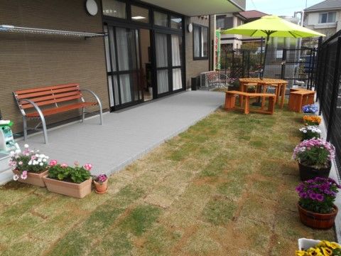 芝生の庭には、鉢に植えられた色とりどりの花が並んでいる。木製のパラソルテーブルセットも置かれており、気分転換にピッタリの場所である。