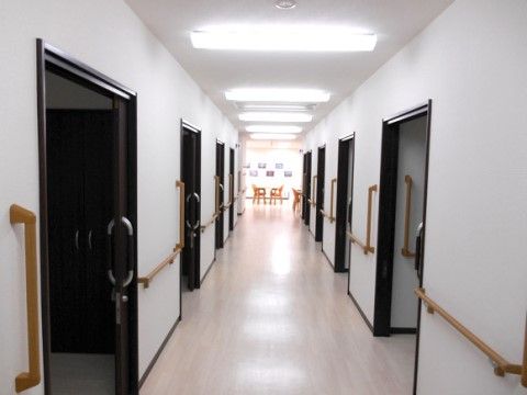 廊下の両側には手すりがあり、引き戸の居室が並んでいる。廊下の壁や天井、フローリングの床は白で統一されていて、明るい雰囲気になっている。
