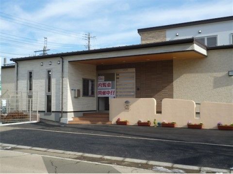 内覧会を開催している白とクリーム色の外壁の施設外観