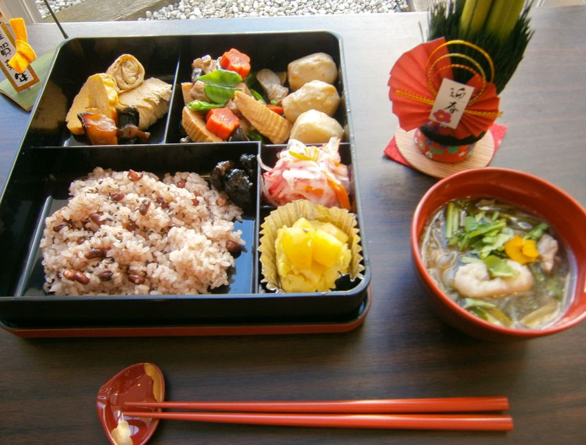 器に盛られた雑煮と重箱に詰められたおせち料理
