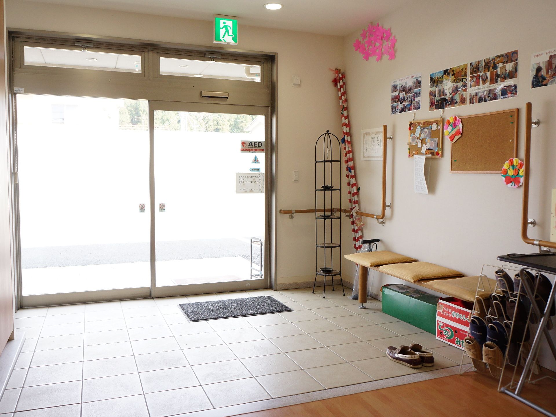 明るく広い玄関。完全フラットのバリアフリーで、長椅子やスリッパたて、壁にはたくさんの写真が貼られている。