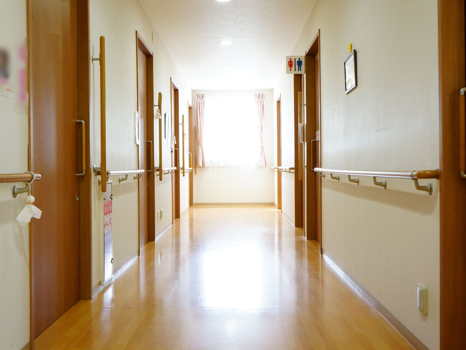 明るい廊下の突き当りは窓で、ゆったりとした幅があり、手すりが設置してある。トイレがある。消火栓が設置されている。
