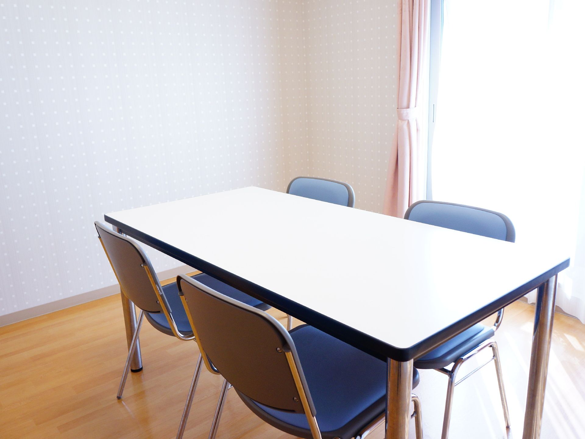 こじんまりとした部屋は、外からの光でとても明るい。4人掛けテーブルセットが一つある。ピンクのカーテンが付いている。