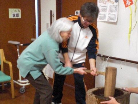 男女2人がかりで杵を持ち臼へと打ち下ろす餅つきの風景