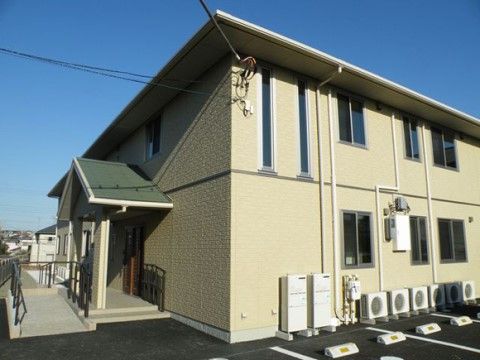 淡いイエローの外壁が特徴的な2階建ての施設の入口外観