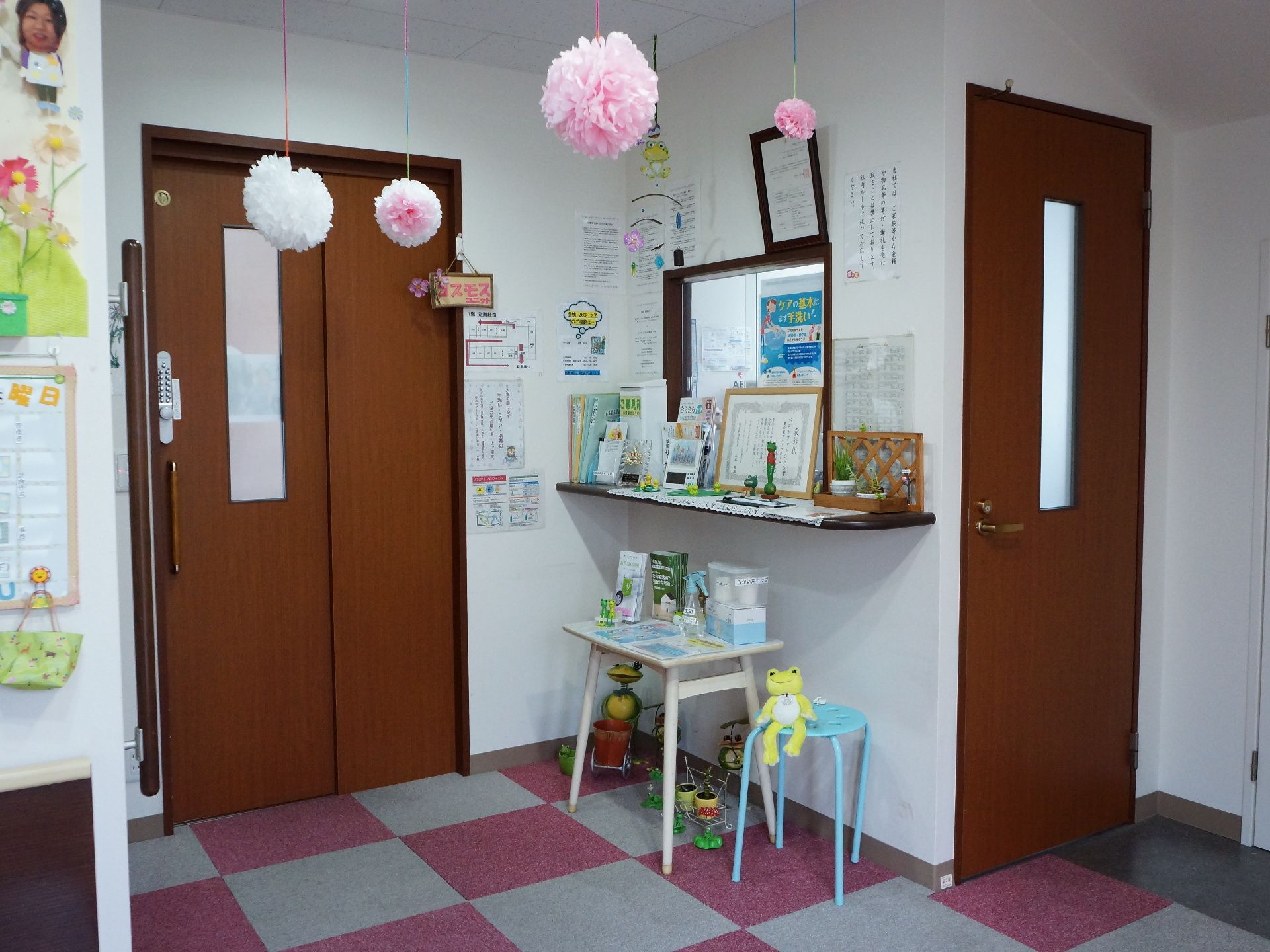 館内の様子。天井からは花の飾りがつるされている。床面はピンクと白のマットが敷かれ、カエルのマスコットや壁面の飾りが見られる。