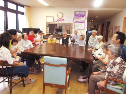 大きなテーブルの周りを隙間なく並んで囲むたくさんの入居者