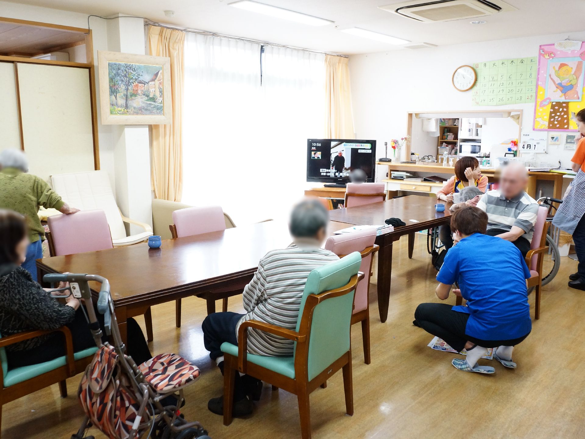 多目的スペースで何人ものお年寄りとスタッフが団欒したりくつろいだりしている。隣にふすまのある部屋がある。