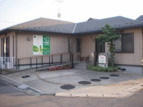 飛び石をモチーフにしたようなコンクリートの前庭を備えた施設外観