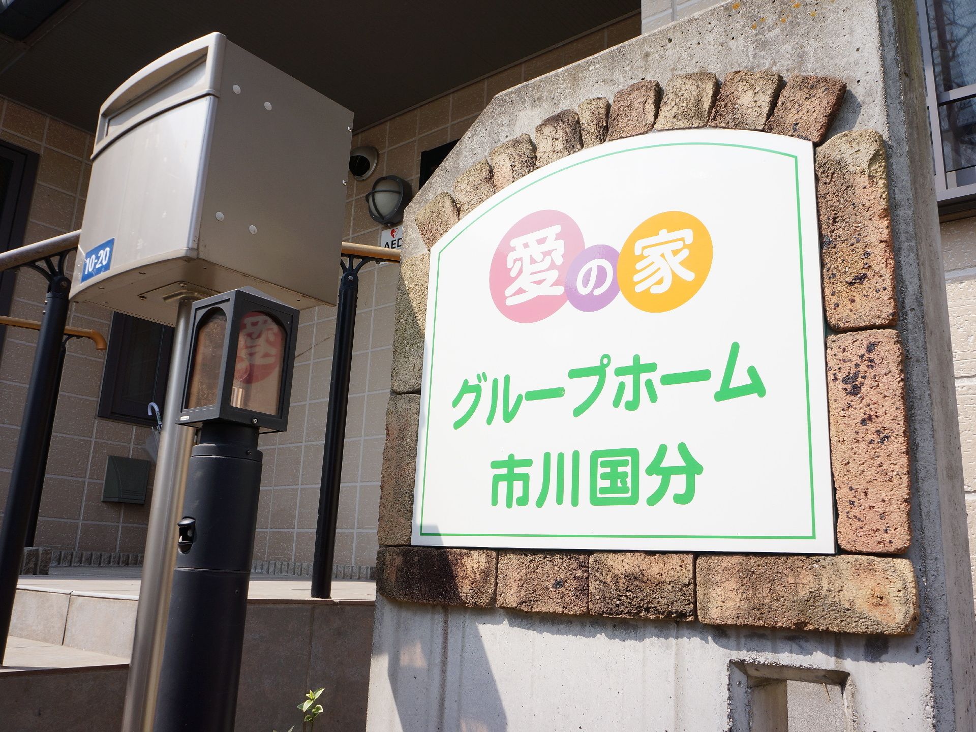 椅子に座って、にこやかな表情で女性スタッフによる血圧測定を受ける女性入居者様