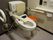 ウォシュレットつき洋式トイレは、背もたれと肘掛けつきの固定手すりが設置されている。呼び出しボタンが手元の1番近くについている。