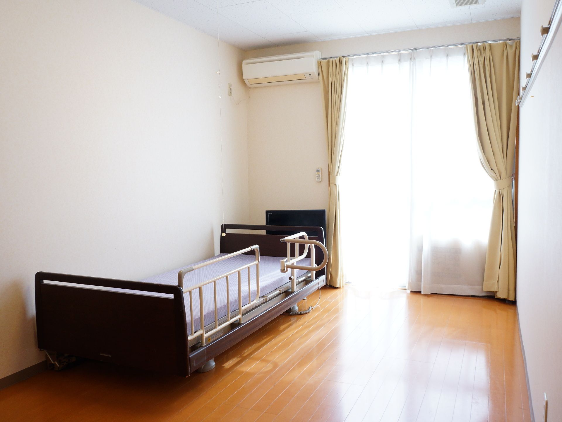 部屋にはベッドとエアコン、カーテンも取り付けられている。カーテンを開けると窓から光が差し込み、部屋が明るくなる。