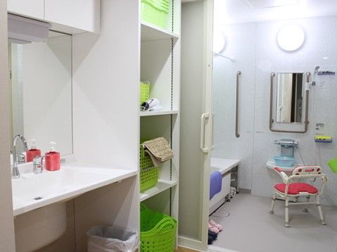 浴室には浴槽やシャワーが設置されていて、専用椅子があり、手すりも各所に付いているので安心して入浴できる。脱衣所には大きめの洗面台がある。