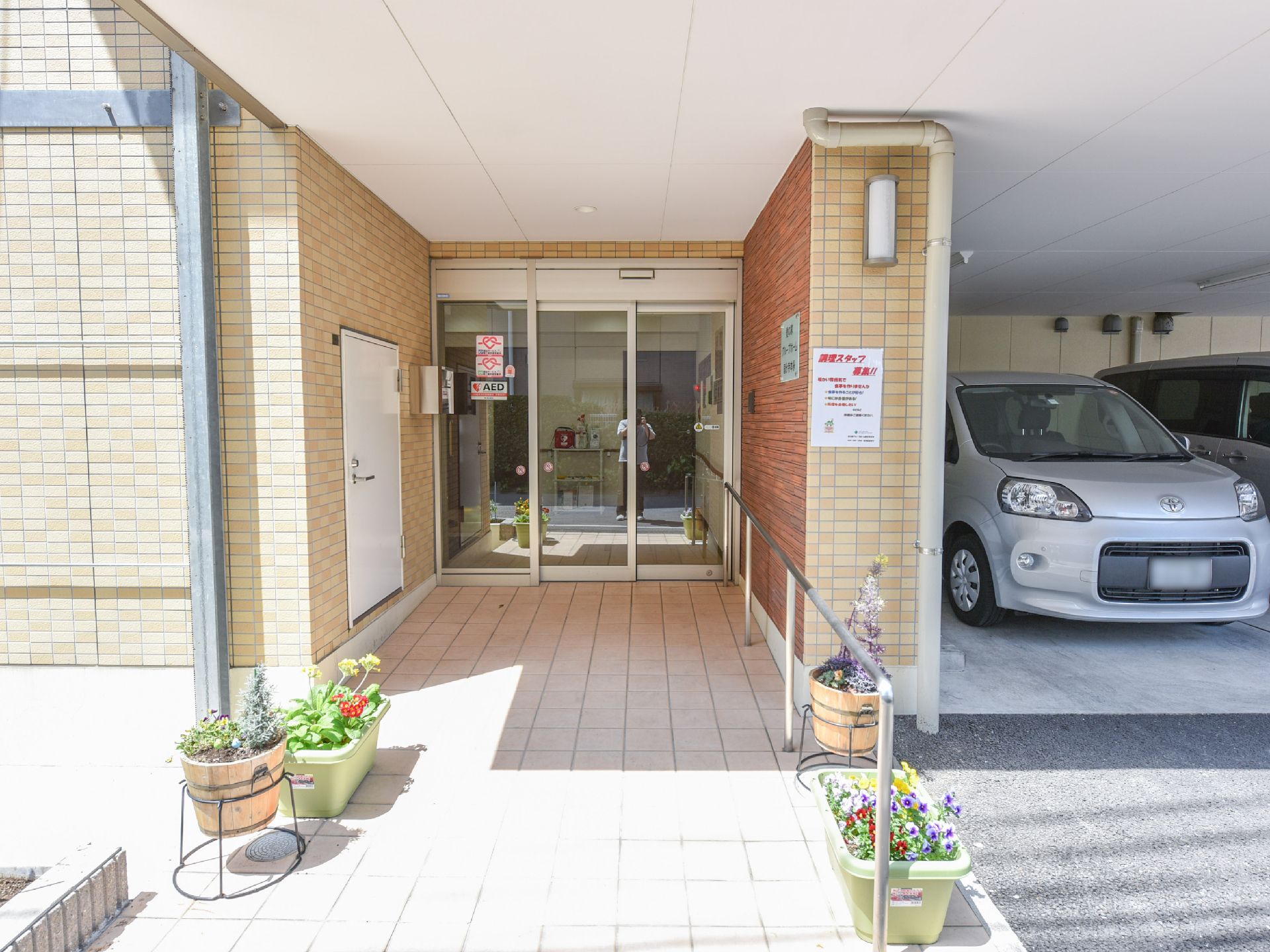 入り口の外観。スロープのため、車椅子の方でも安心して入居ができる。入り口の通路脇にはプランターが置かれており、明るい印象。