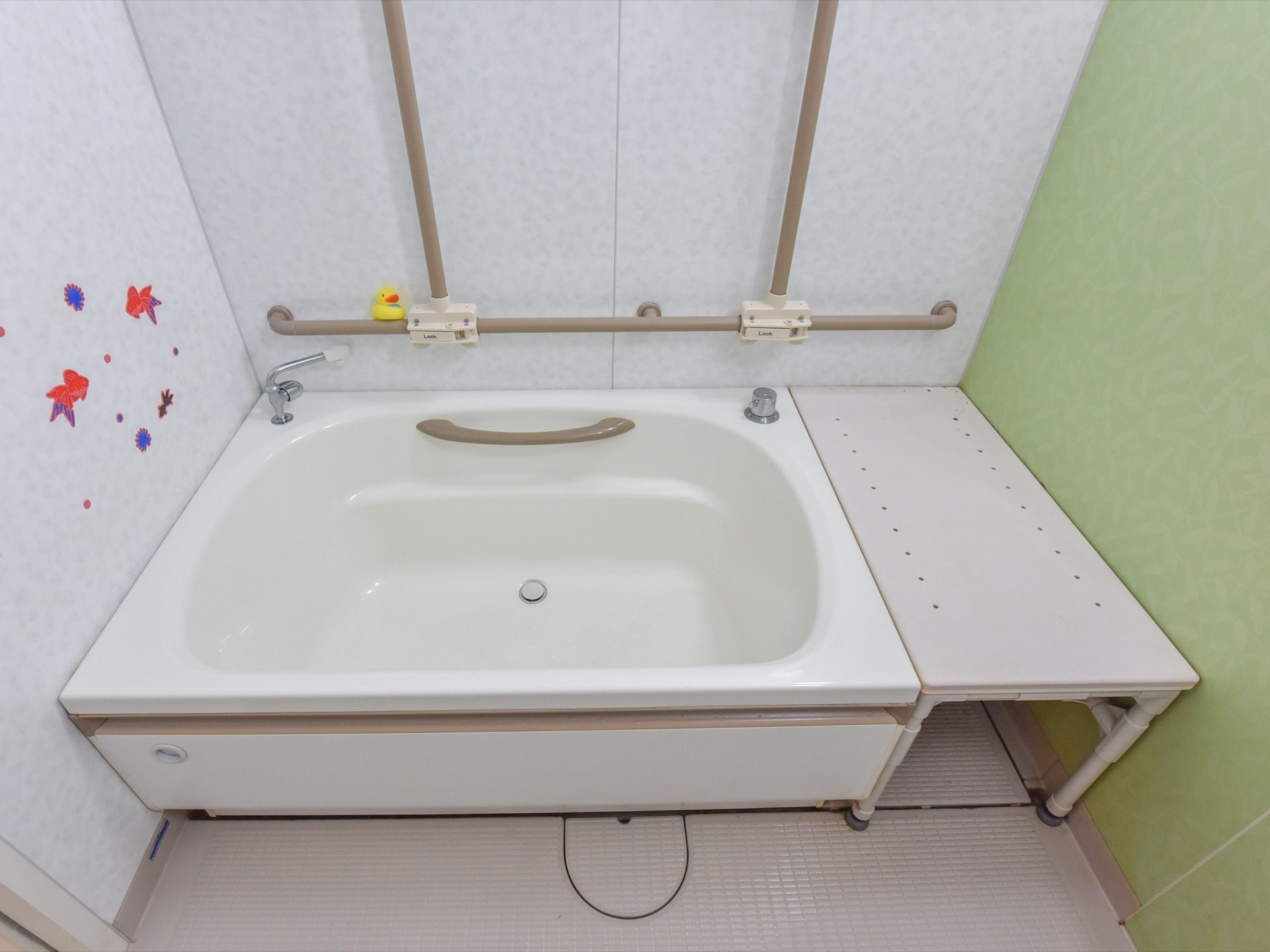 浴槽の壁には縦方向と横方向にも手すりが設置されている。すわった姿勢で浴槽に入れるよう、イスが設置されている。