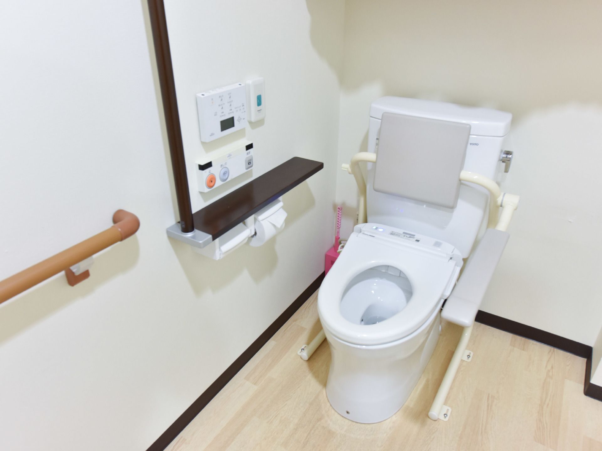 洋式の便座には、背もたれとひじ掛けがあるので、ひじ掛けを支えにして立ち上がることができる。そばには呼び出しボタンもある。
