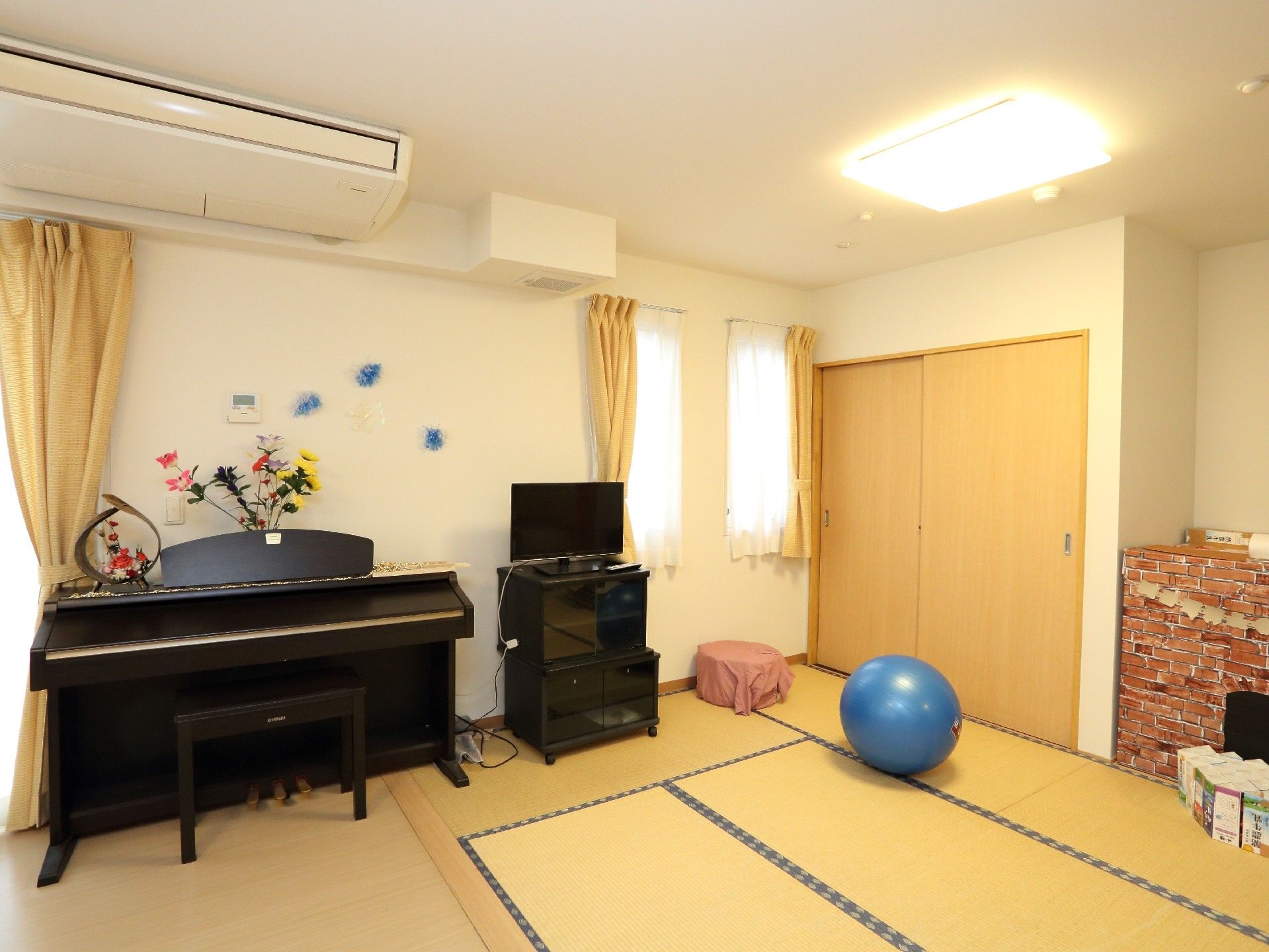 畳の部屋。バランスボールやピアノ、テレビのある落ち着いた雰囲気。