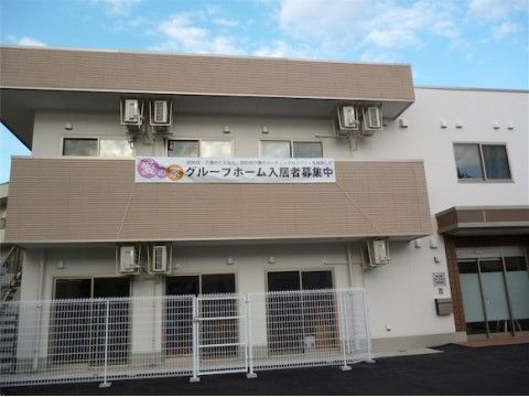 「愛の家グループホーム 足立堀之内」外観です。白と茶のコントラストが安心感を与えます。