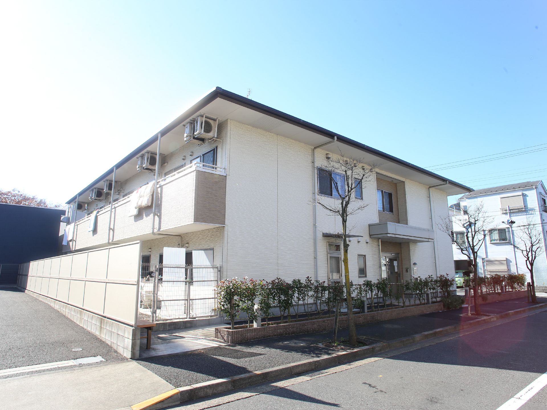 施設は白い2階建てで、普通の賃貸住宅のような外見。2階の部屋にはベランダが設置され、洗濯物が干されている。