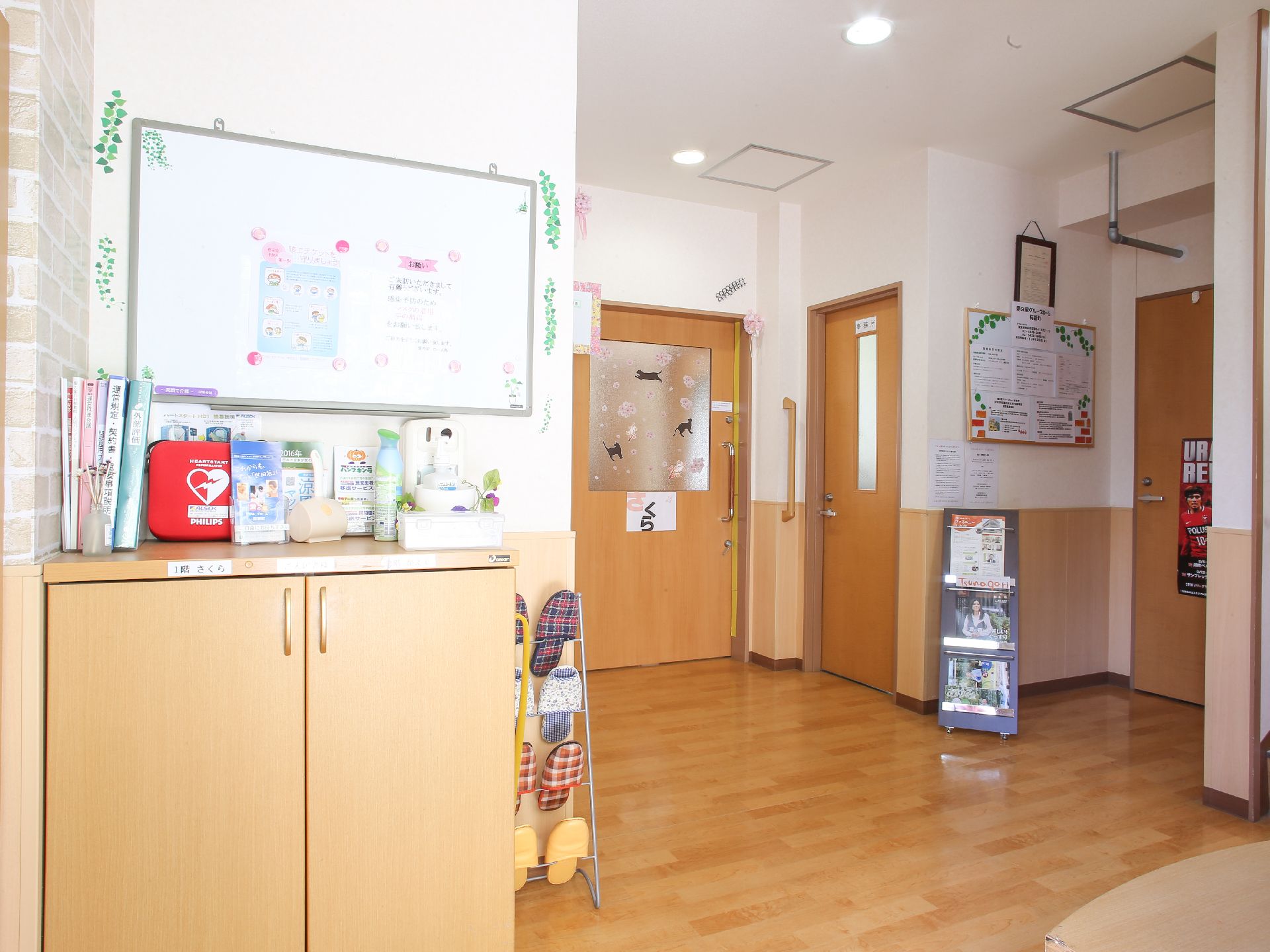 掲示板が2つあり各種張り紙がされている。1つはホワイトボードになっている。棚があり、その上にはAEDが置かれている。